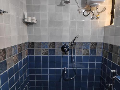 y baño con ducha de azulejos azules. en Patnem Beach park, en Canacona