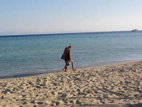 a woman walking on the beach near the water at Altinersan Hotel in Didim