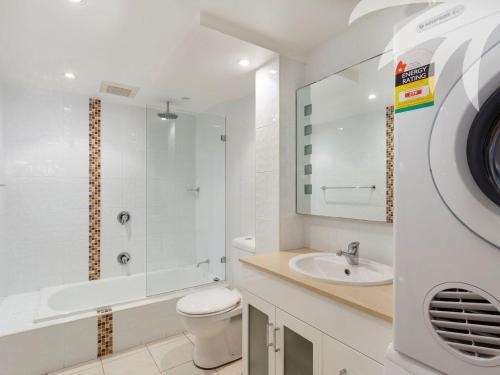 a white bathroom with a toilet and a sink at Oceanside 17 Breezes in Blueys Beach