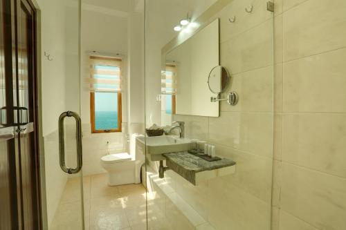 a bathroom with a toilet and a sink and a mirror at Morven Hotel Colombo in Colombo