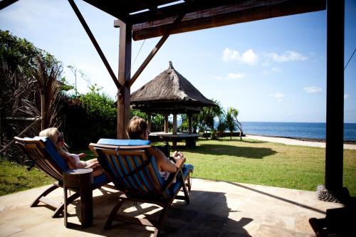 two people sitting in chairs on a patio looking at the ocean at Jasri Bay Hideaway in Jasri
