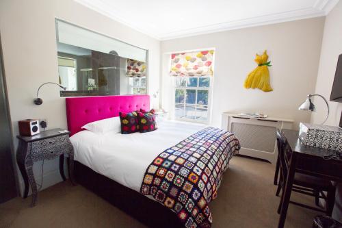 a bedroom with a bed with a pink head board at Hartnoll Hotel & Spa in Tiverton