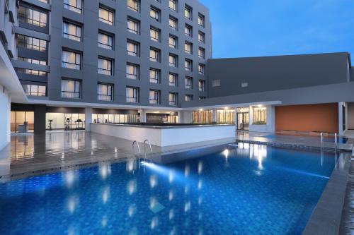 einem Hotelpool vor einem Gebäude in der Unterkunft Harper Palembang by ASTON in Palembang