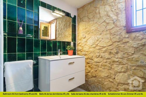 a bathroom with a sink and a stone wall at SolHabitat Villa Big Blue in Benissa