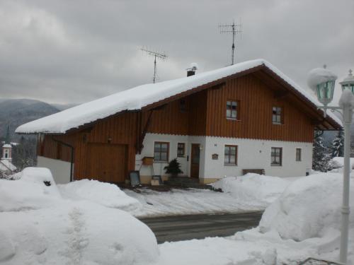 a house with snow on the roof of it at Ferienwohnungen Winter in Lohberg