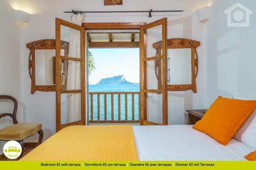 a bedroom with a bed and a view of the ocean at SolHabitat Villa Papavents in Benissa