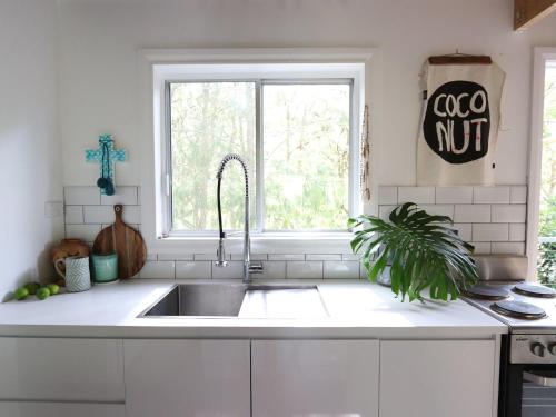 cocina blanca con fregadero y ventana en The Shaka Shack, en Smiths Lake