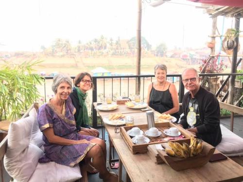 a group of people sitting around a table on a balcony at ST 63 Home Stay & Tour Kampong Khleang in Kâmpóng Khleăng