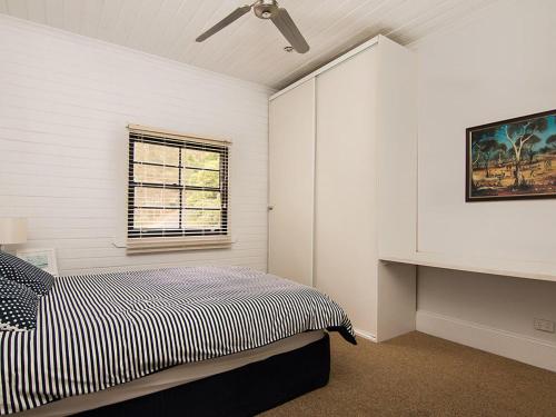 a white bedroom with a bed and a window at Tuppys on the Lake in Neranie