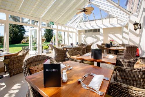 a restaurant with wooden tables and chairs and windows at Hartnoll Hotel & Spa in Tiverton