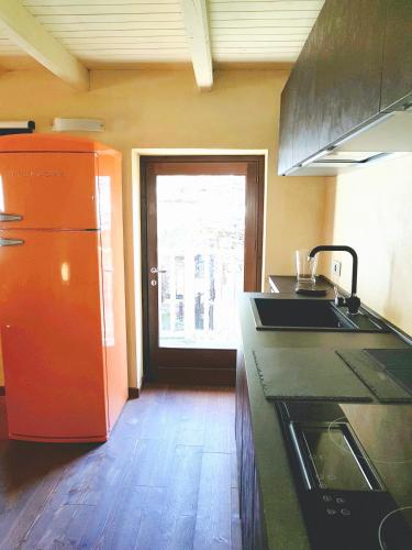 a kitchen with a sink and an orange refrigerator at Villa Ottocento in Campertogno