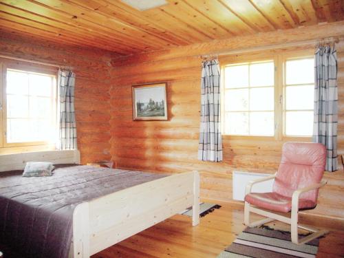 a bedroom with a bed and a chair and windows at Loma-Pälsilä lakeside villa in Kuhmoinen