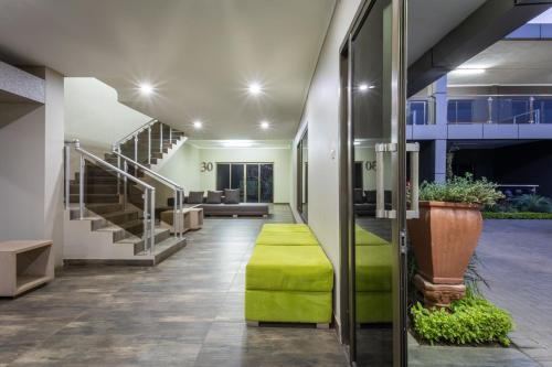 a lobby with stairs and a green ottoman at Fallsway Suites in Lusaka