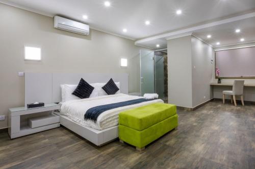a bedroom with a bed and a green ottoman at Fallsway Suites in Lusaka