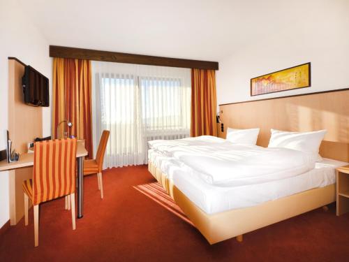 a hotel room with a large bed and a desk at Seligweiler Hotel & Restaurant in Ulm