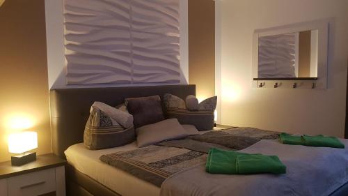 a bedroom with a bed with green pillows and a mirror at Pension Hoefti in Chemnitz