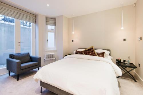 a bedroom with a white bed and a chair at Home Sweet Hampstead Heath in London