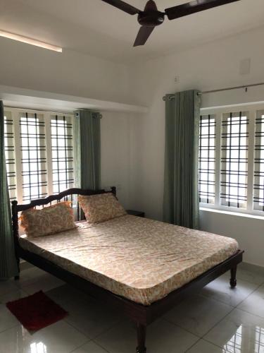 Schlafzimmer mit einem Bett mit grünen Vorhängen und einem Deckenventilator in der Unterkunft Sannidhi Home stay in Guruvāyūr