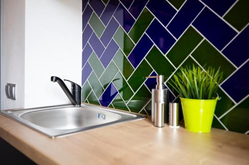 a kitchen counter with a sink and a tile wall at Old Town Courtyard Apartment with private parking in Cluj-Napoca