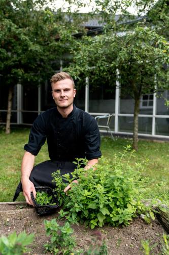 a man is holding a plant in a garden at Vilcon Hotel & Konferencegaard in Slagelse