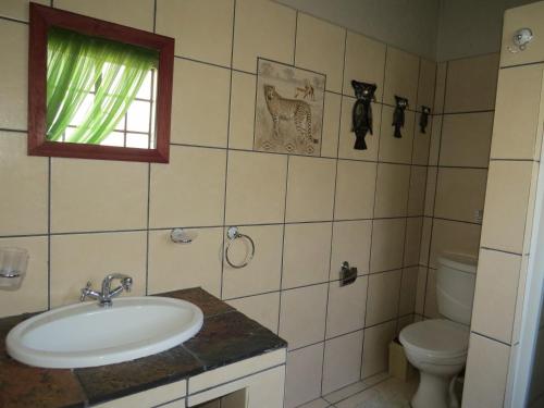 a bathroom with a sink and a toilet and a window at Bellamia in Marloth Park