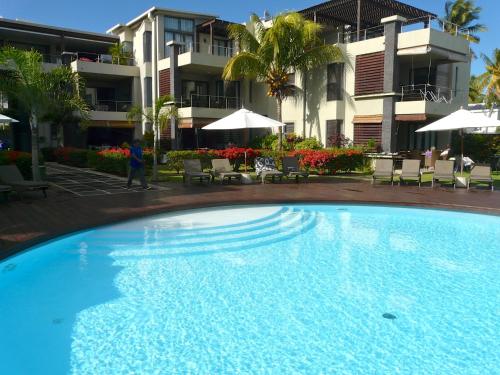 une grande piscine en face d'un bâtiment dans l'établissement Troux aux Biches Le Cerisier A2 Mauritius, à Trou aux Biches