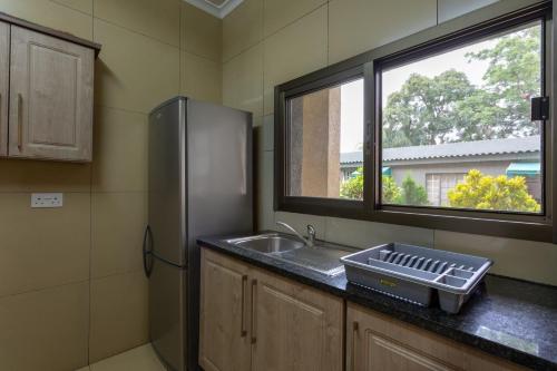 a kitchen with a sink and a refrigerator at Fallsway Apartments - Burley Court in Lusaka