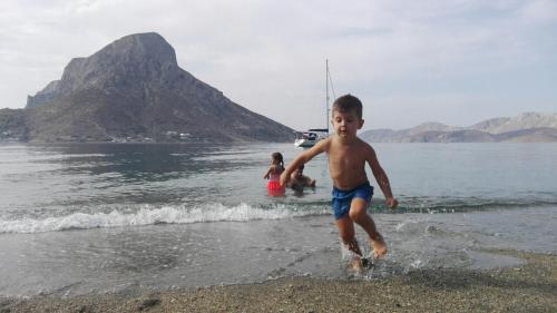 a young boy running on the beach in the water at Elenis Studios&Apartments in Masouri