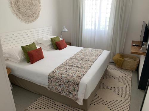 1 dormitorio con 1 cama grande con almohadas rojas y verdes en OBiches Luxury Beachfront Apartment Trou-aux-Biches, en Trou aux Biches