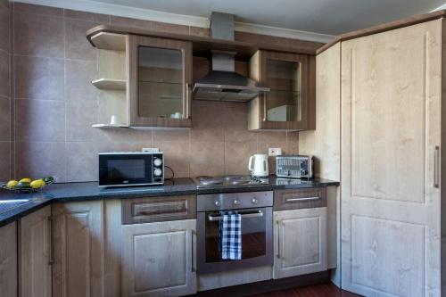 a kitchen with wooden cabinets and a stove top oven at Fallsway Apartments - Louden Court in Lusaka