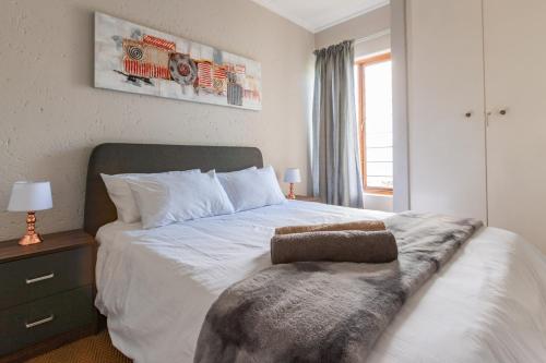 Un dormitorio con una gran cama blanca con una manta. en Alimama Spaces: Manson's Bedford Haven, en Johannesburgo