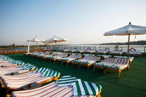 a row of lounge chairs and umbrellas on a beach at Nile Carnival Cruise 4nt Lxr Thursday 3nt Asw Monday in Luxor