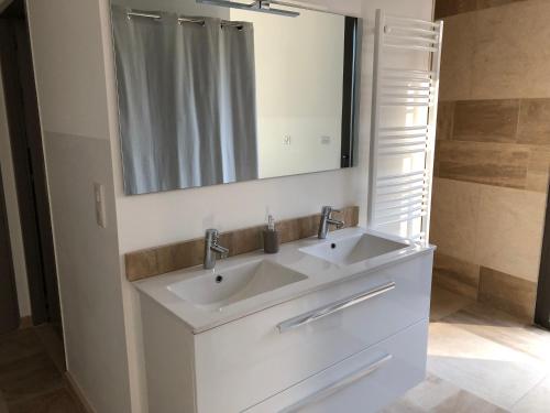 ein Badezimmer mit einem weißen Waschbecken und einem Spiegel in der Unterkunft Le Pakok in Lit-et-Mixe
