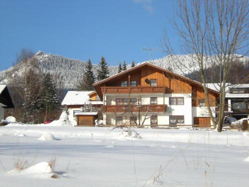 a large wooden house in the snow in front at Ferienwohnungen Winter in Lohberg