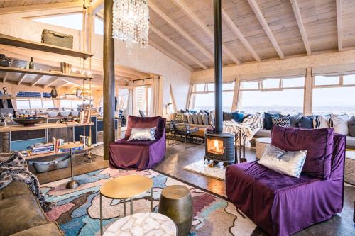 a living room with purple furniture and a fireplace at Shipwreck Lodge in Möwebaai