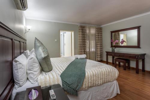 a bedroom with a bed with a desk and a mirror at Fallsway Apartments - Louden Court in Lusaka