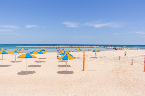 a beach with many umbrellas and the ocean at Hotel Dreams Beach in Hammam Sousse