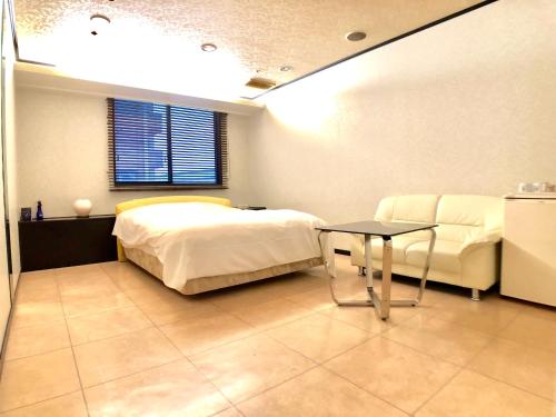 a bedroom with a bed and a table and a couch at Hotel Ritz Koshien in Nishinomiya