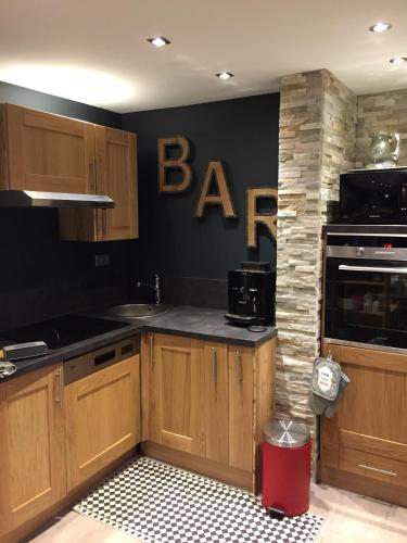 d'une cuisine avec des placards en bois et un panneau de protection sur le mur. dans l'établissement L'Appart de l'Arche, à Peisey-Nancroix