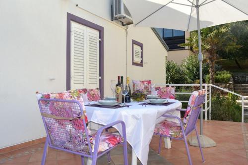 a table with chairs and an umbrella on a patio at Apartment Ravni 1337 in Ravni