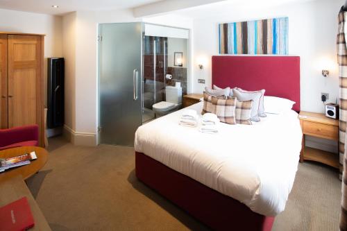 a hotel room with a large bed and a bathroom at Hartnoll Hotel & Spa in Tiverton