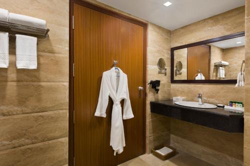 a bathroom with a sink and a robe hanging on a door at Ramada Jamshedpur Bistupur in Jamshedpur