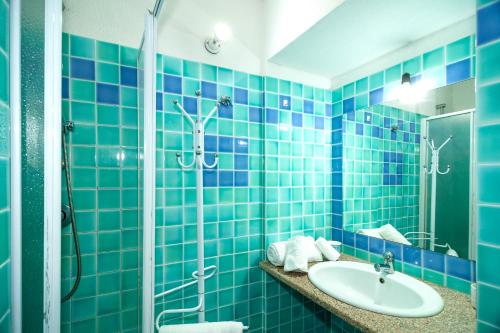 a blue tiled bathroom with a sink and a shower at Stella Marina Budoni in Budoni