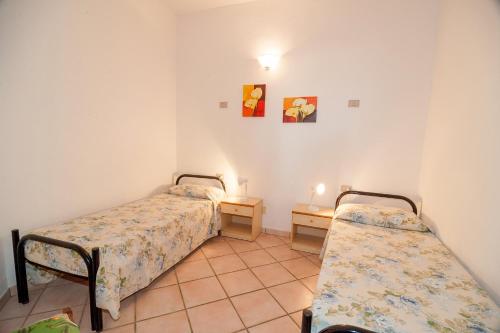 a room with two beds and a table with a lamp at Stella Marina Budoni in Budoni