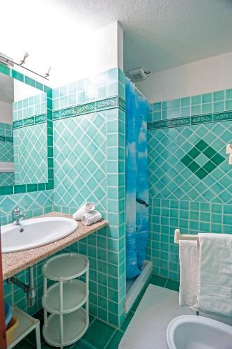 a blue tiled bathroom with a sink and a tub at Stella Marina Budoni in Budoni