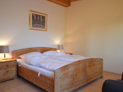 een groot houten bed in een kamer met 2 lampen bij Spacious Eifel Escape in Manderscheid