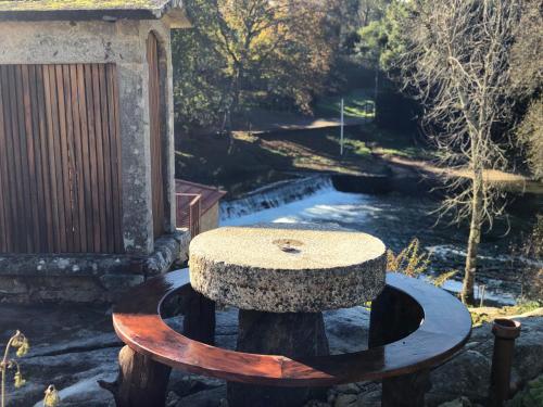 a stone bench sitting on a tree stump next to a river at Azenha do Tio Luís in Caminha