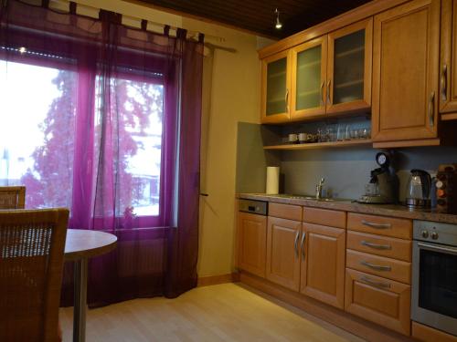 een keuken met houten kasten, een raam en een tafel bij Spacious Eifel Escape in Manderscheid