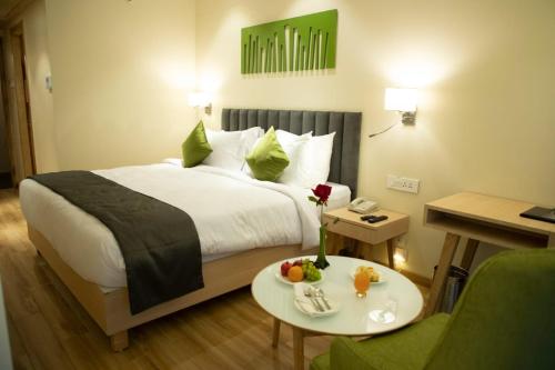 a hotel room with a bed and a table with fruit on it at Regenta Central Harsha Vapi in Vapi