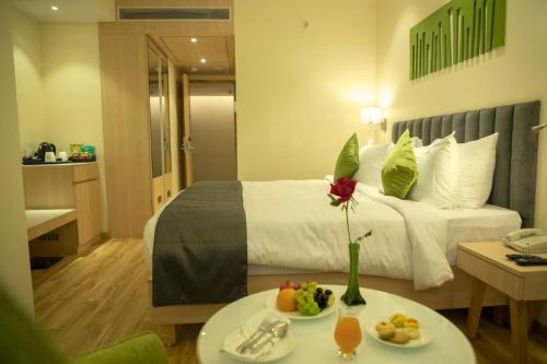 a hotel room with a bed and a table with food on it at Regenta Central Harsha Vapi in Vapi